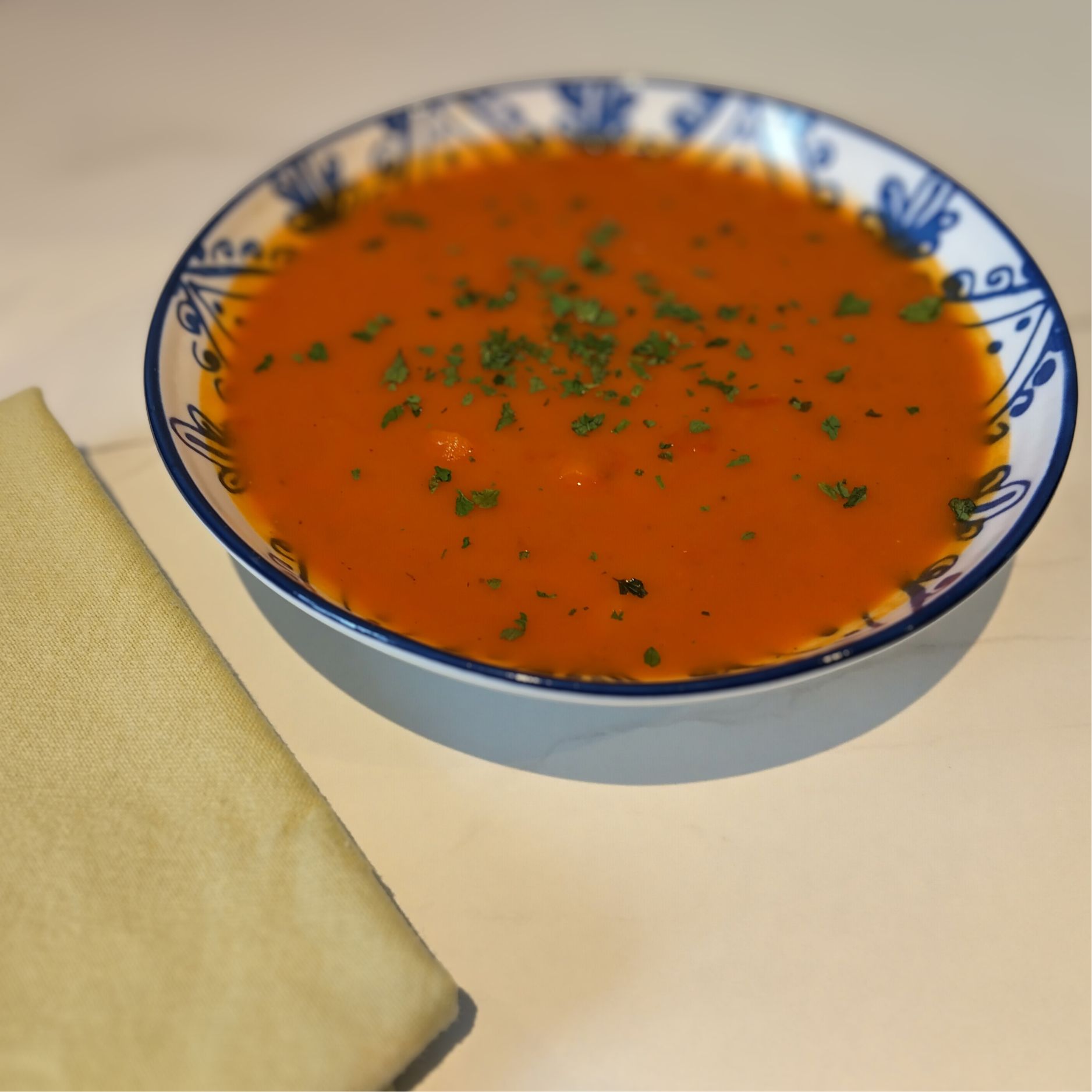 Carrot and butter bean soup with parsley on top next to a green napkin
